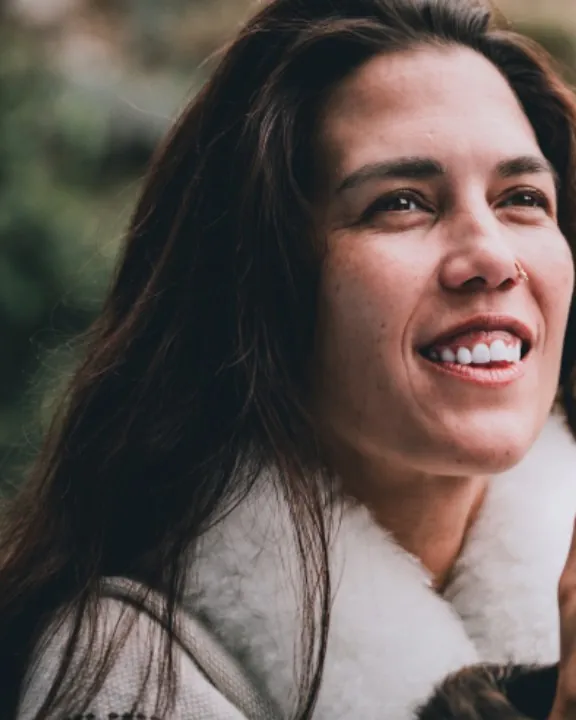 Shāradā smiling warmly, a white shawl around her shoulders